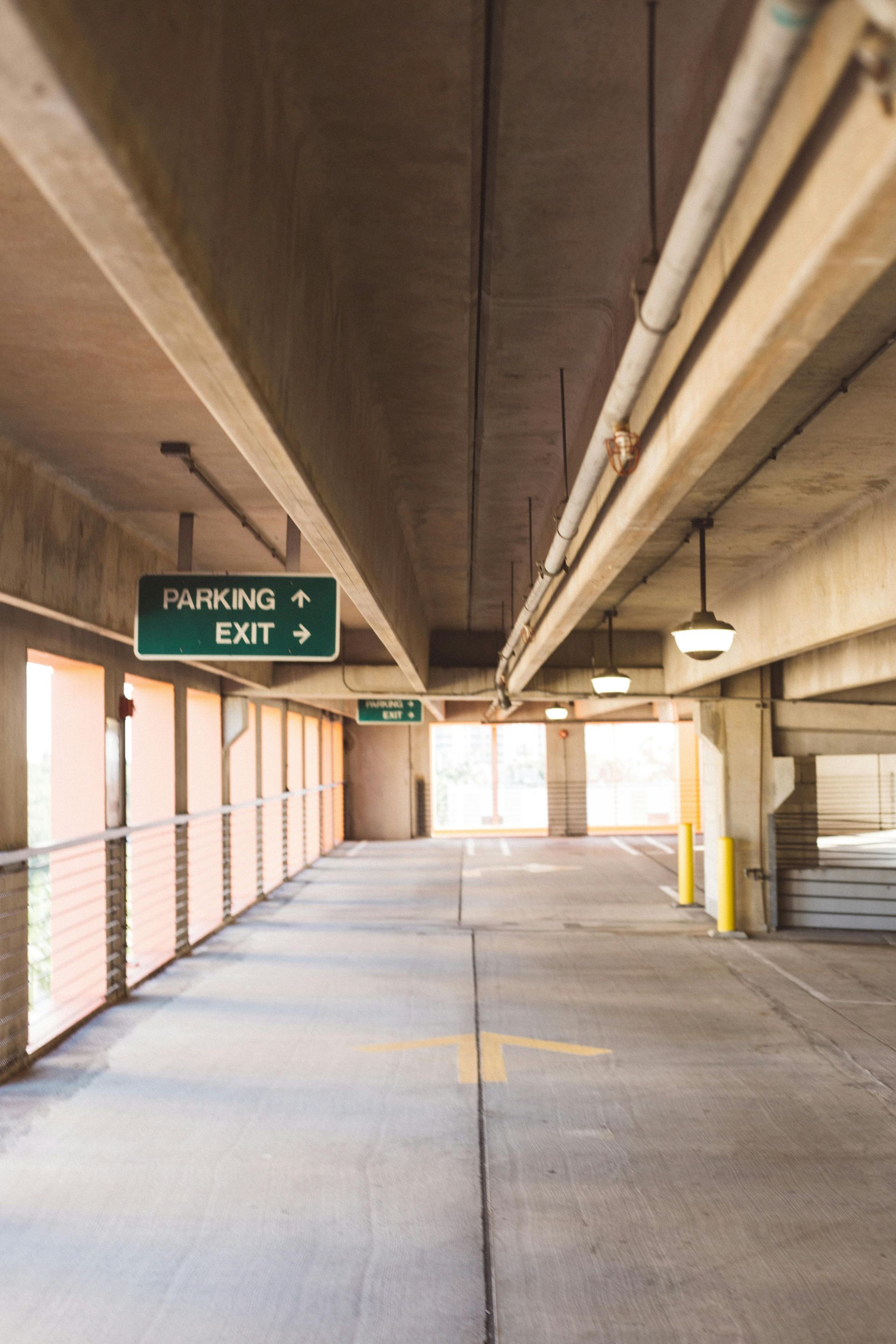 A long hallway in a parking garage with a sign that says parking exit.