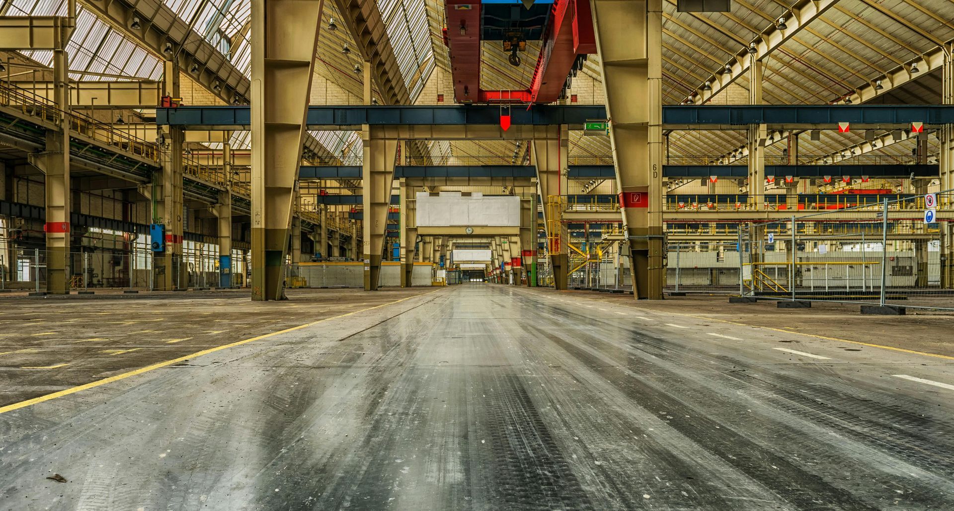 An empty factory with a crane in the middle of it.