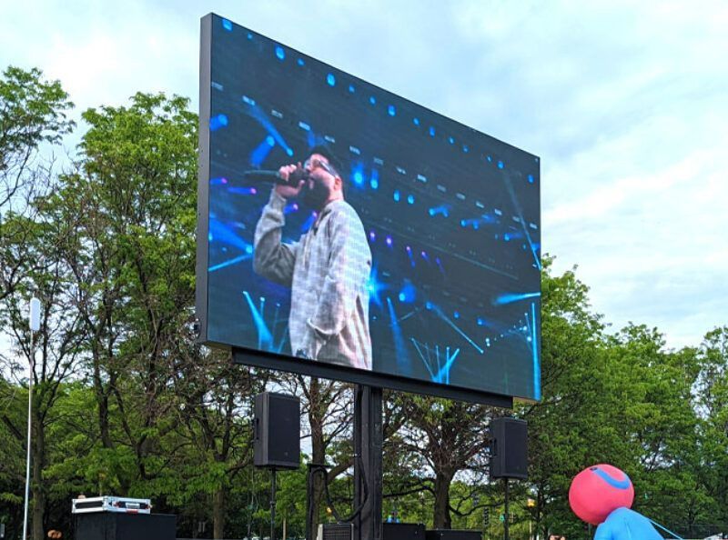 A large screen shows a man singing into a microphone.