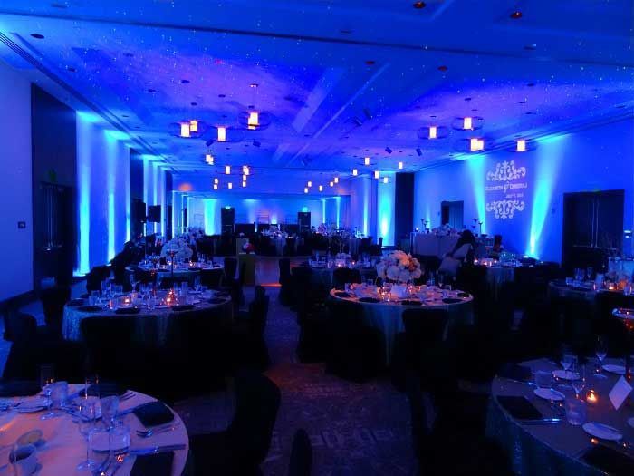 A large room filled with tables and chairs is lit up with blue lights.