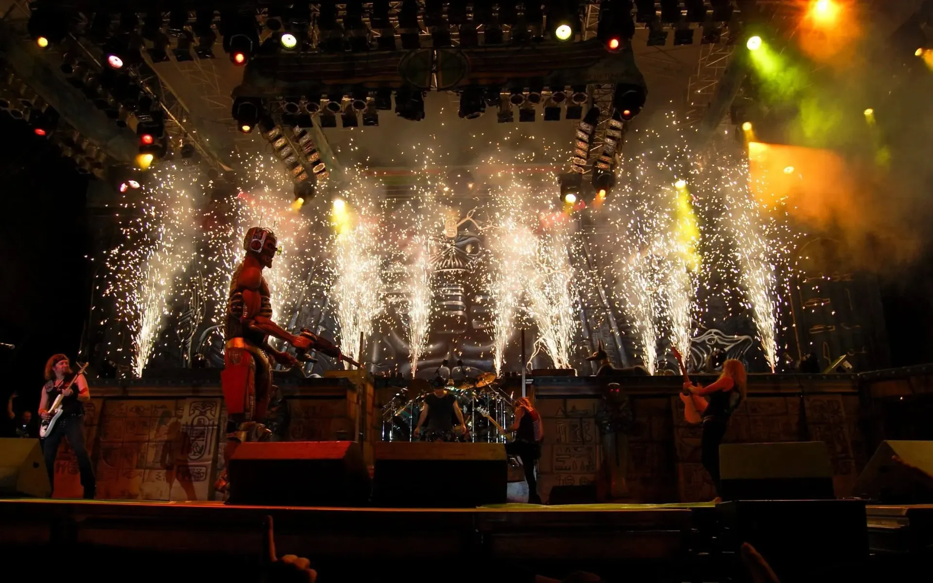 A man is standing on a stage in front of a fireworks display.
