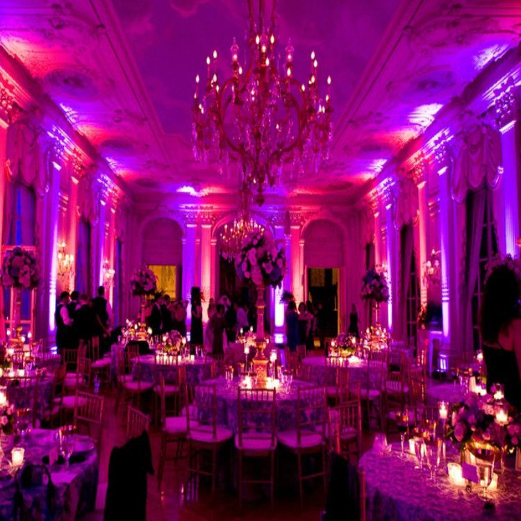 A large room filled with tables and chairs and purple lights.