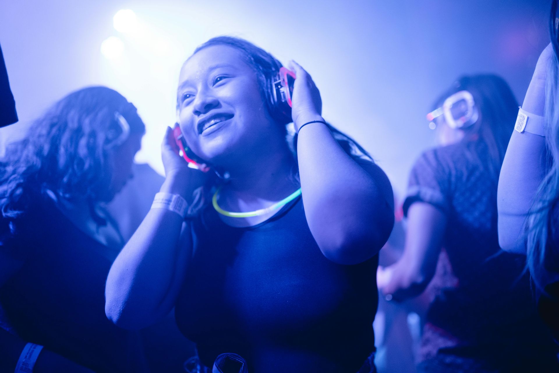 A woman is wearing glow in the dark headphones at a party.