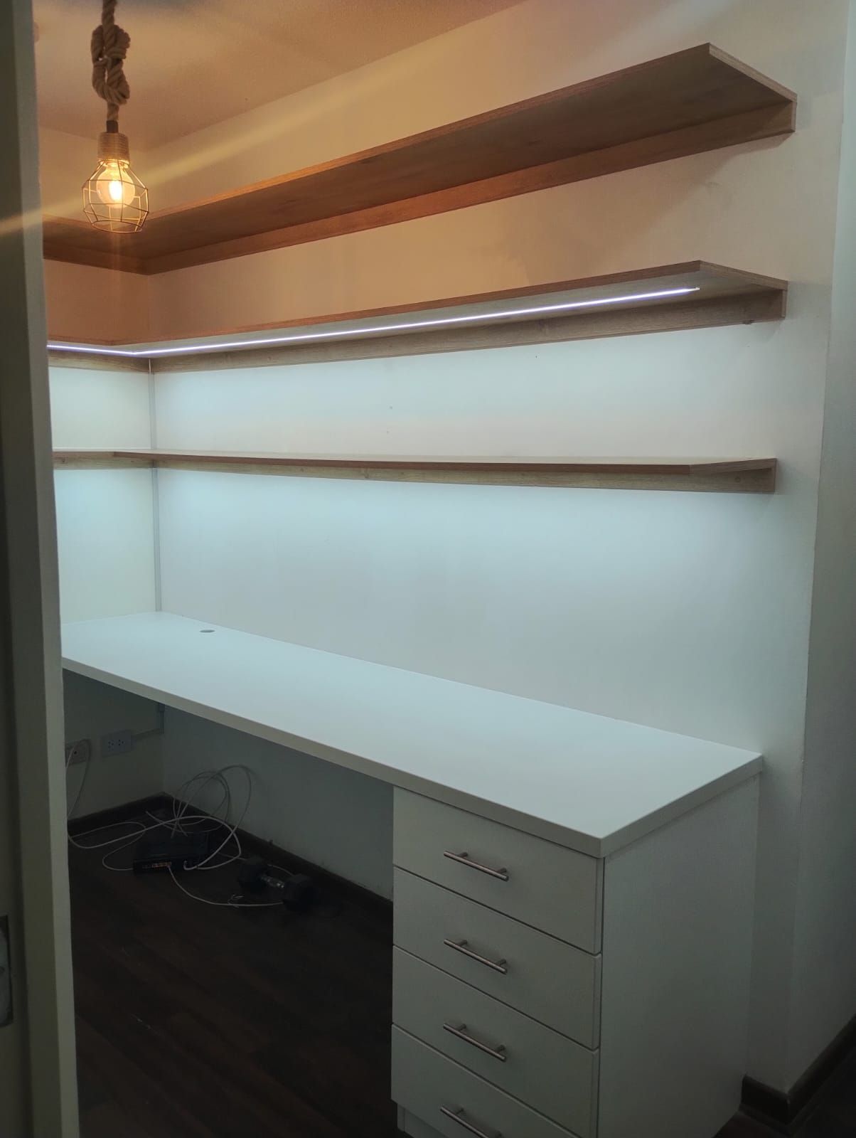 Un escritorio blanco con cajones y estantes en una habitación.