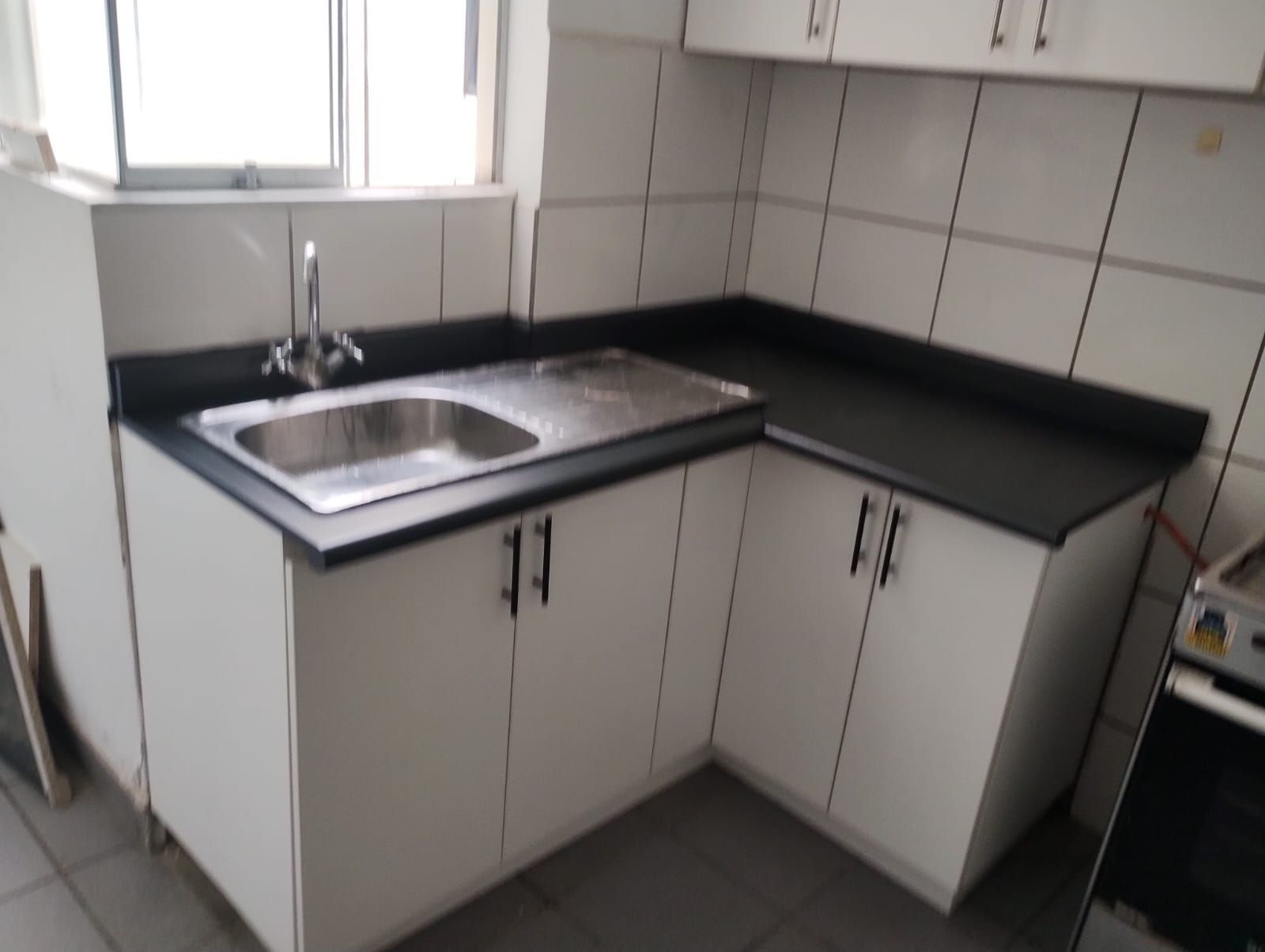 Una cocina con gabinetes blancos y encimeras negras.