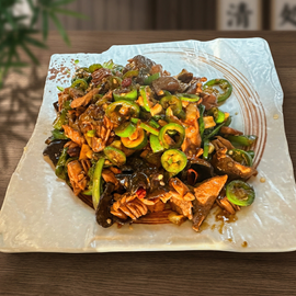 A plate of stir-fried dish featuring sliced meat, wood ear mushrooms, and chopped green chili peppers on a wooden table.