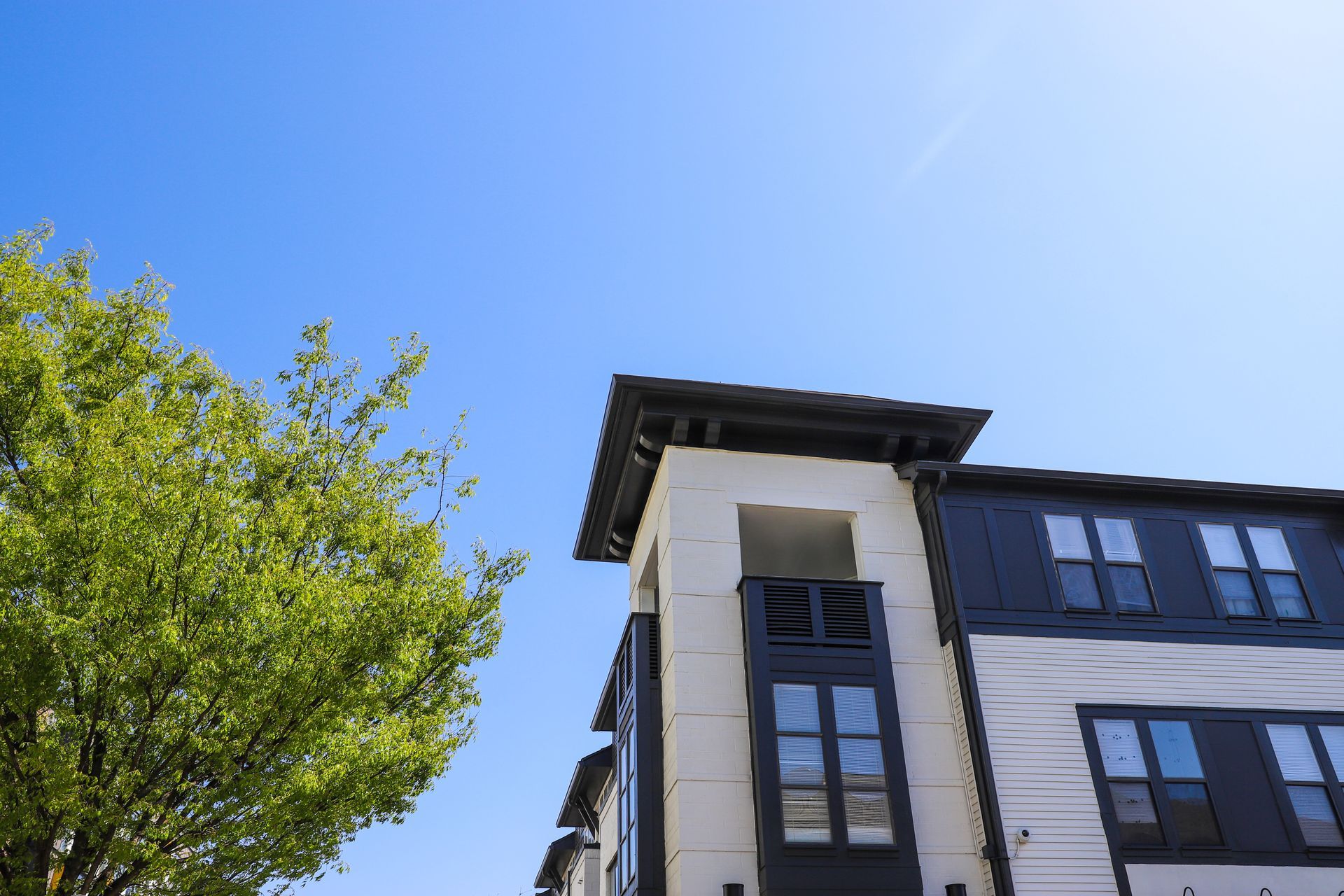 A large apartment building with a tree in front of it and a blue sky in the background.