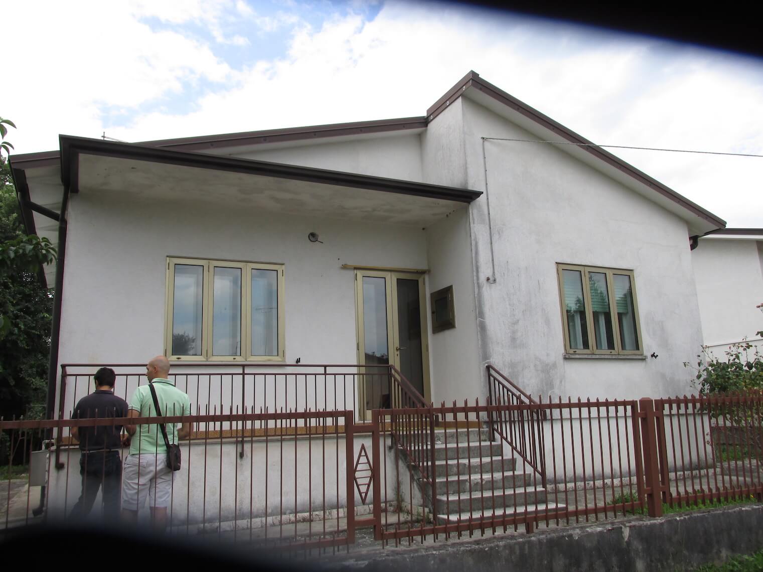 Una casa bianca con una staccionata rossa e le scale