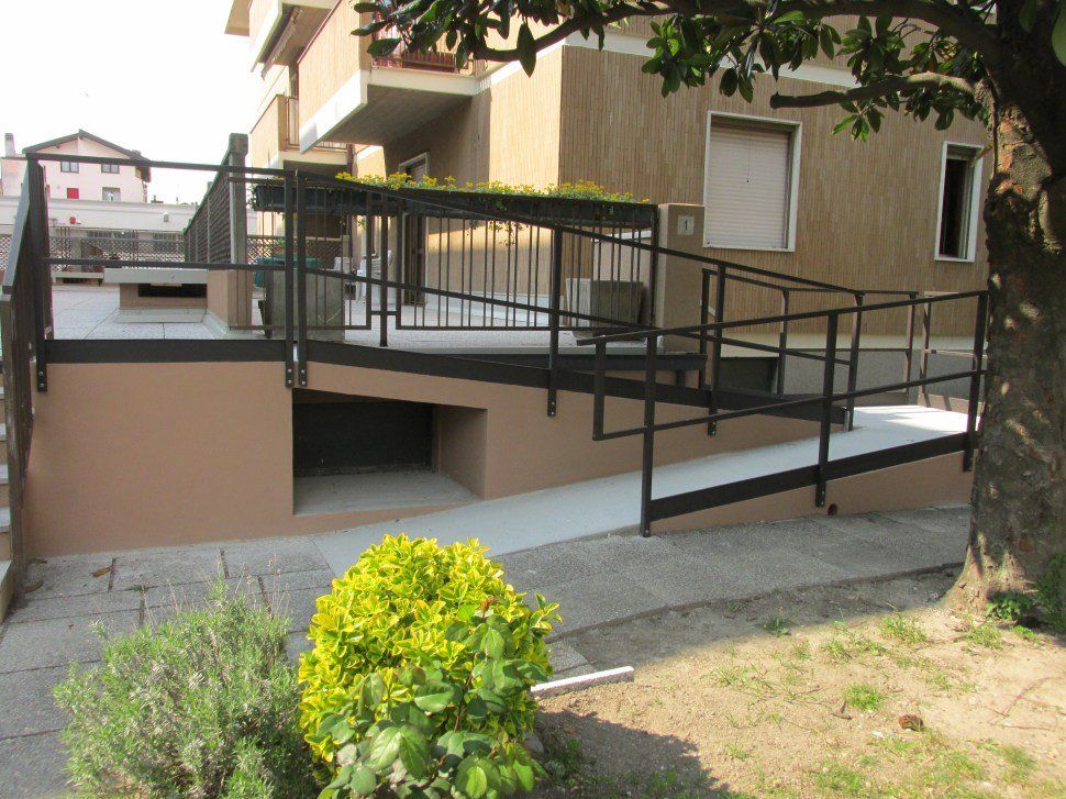 Una rampa che porta a un edificio con un albero in primo piano