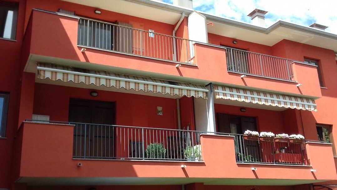 Un edificio rosso con un balcone e una tenda da sole