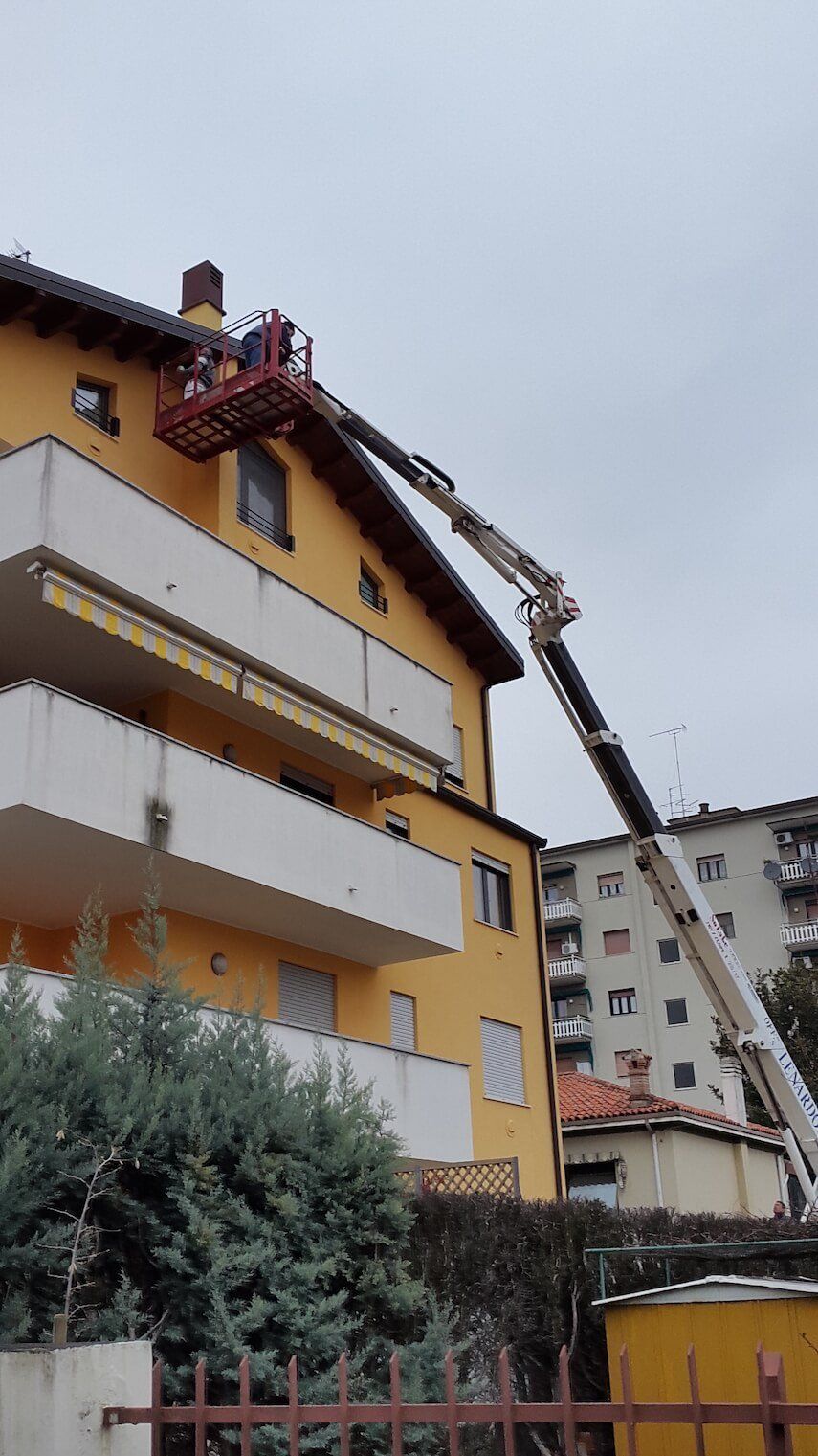 Un uomo sta lavorando sul tetto di un edificio con una gru.