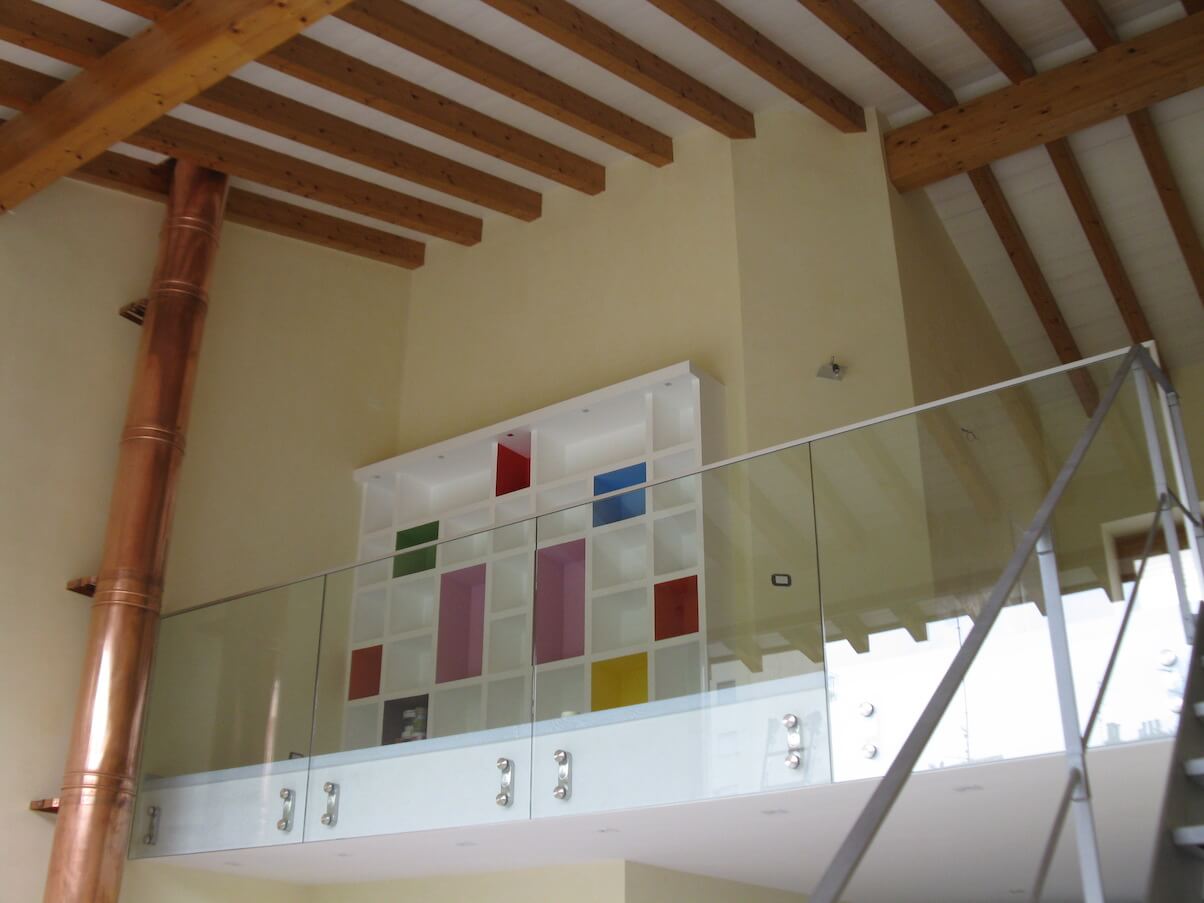 Una scala con una ringhiera in vetro che porta a una libreria