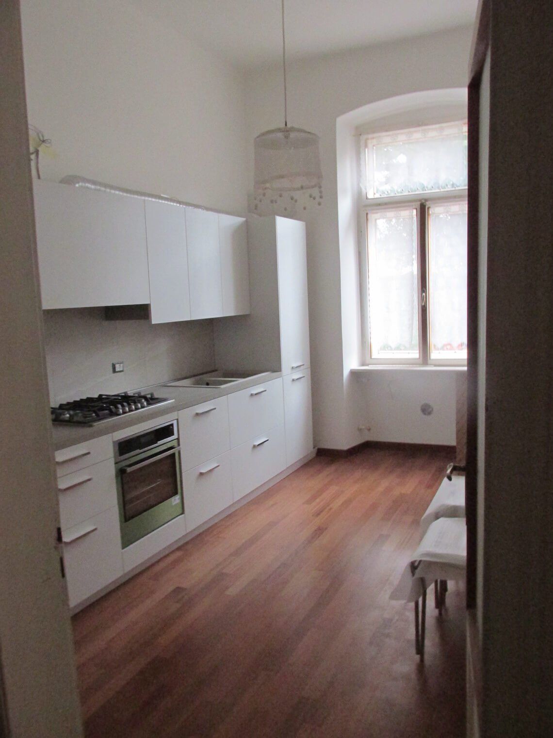 Una cucina con mobili bianchi e pavimenti in legno