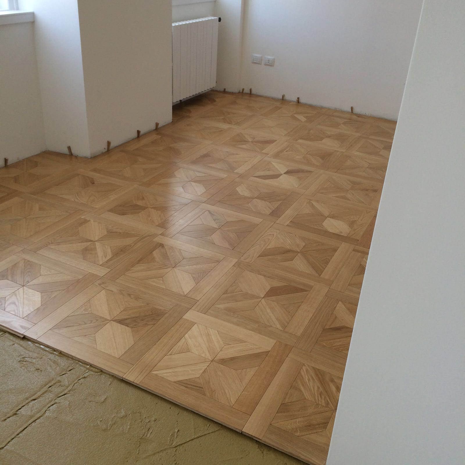 Una stanza con pavimento in legno e pareti bianche