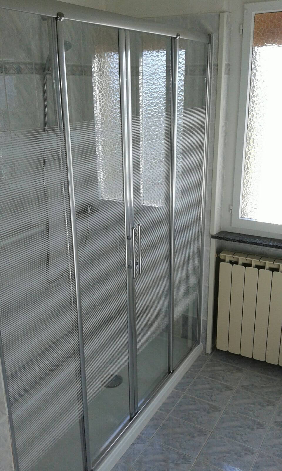 Un bagno con box doccia e termosifone.