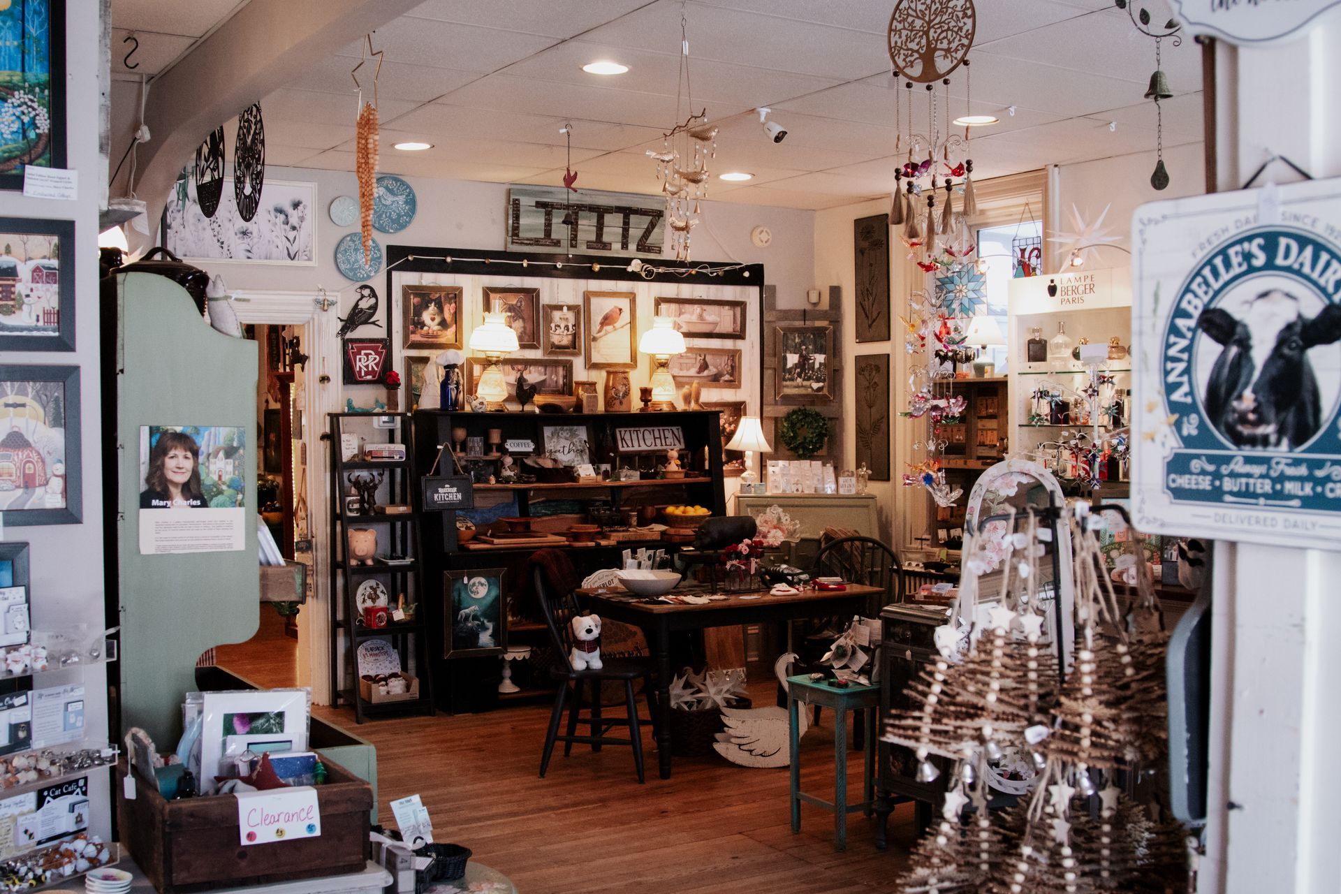 A blue painted dresser with four drawers, wooden top, and black knobs, with a plant and pitcher.