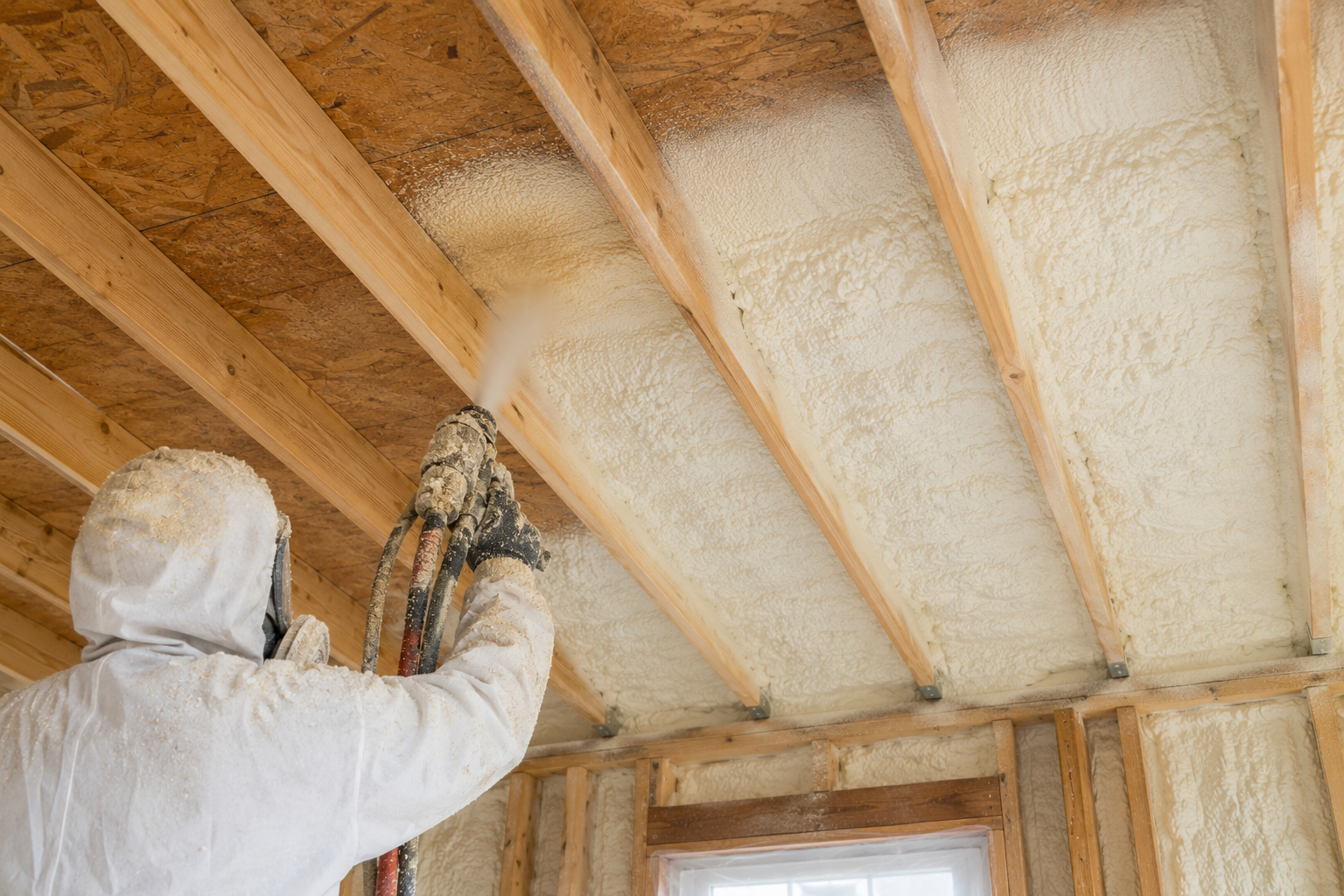A spray foam operator insulating in between the joists of a subfloor