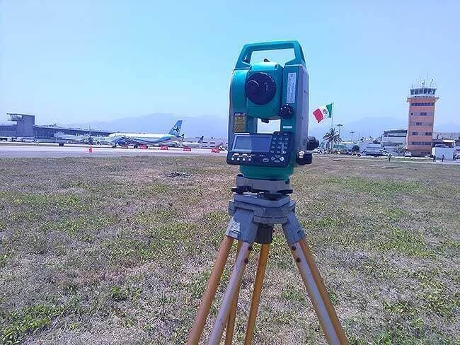 Una cámara verde en un trípode con una bandera mexicana de fondo