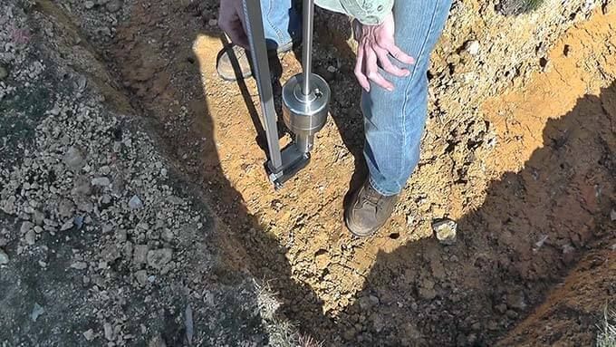 Una persona está usando un taladro para cavar un hoyo en el suelo.
