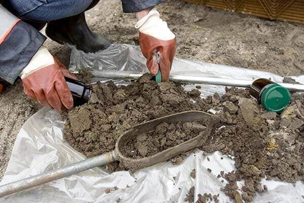 Una persona está sacando tierra de una bolsa con una pala.