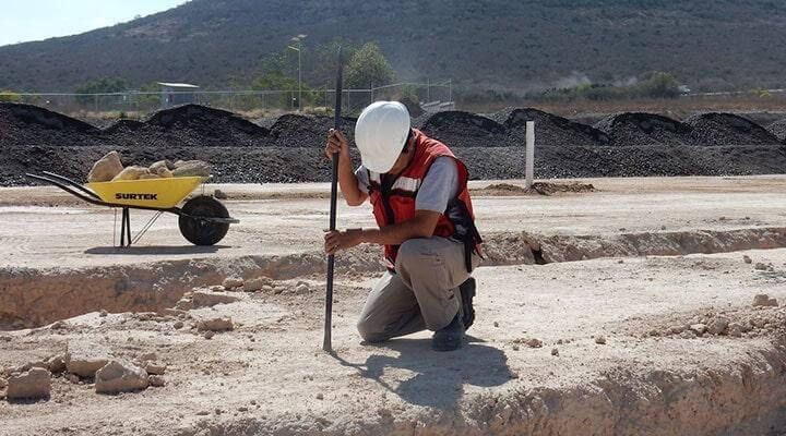 Un hombre está arrodillado en el suelo sosteniendo un palo.