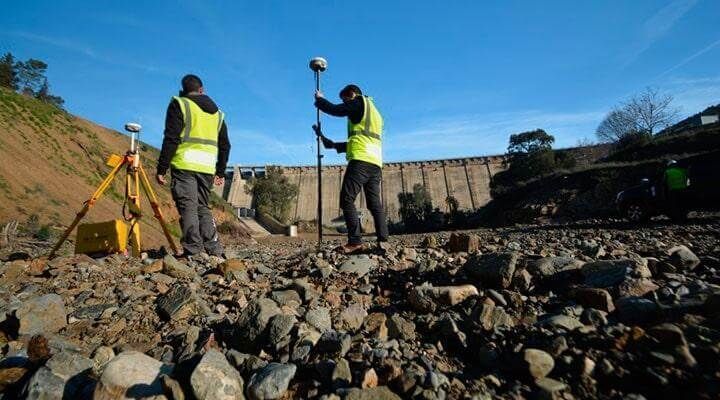 Dos hombres están de pie encima de una pila de rocas.