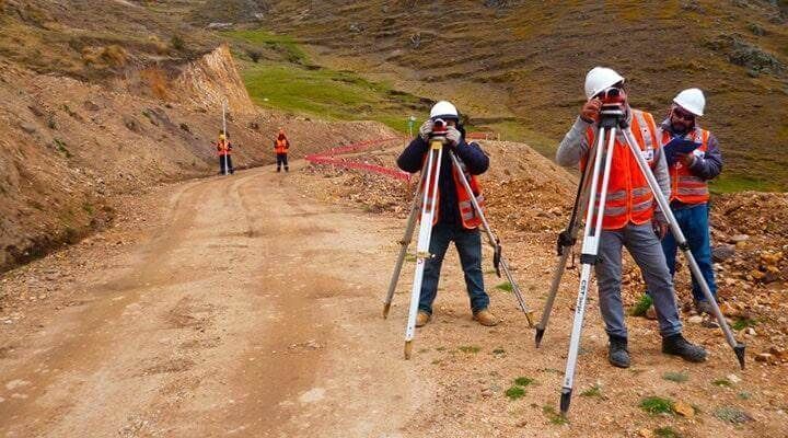 Un grupo de trabajadores de la construcción está trabajando en un camino de tierra.