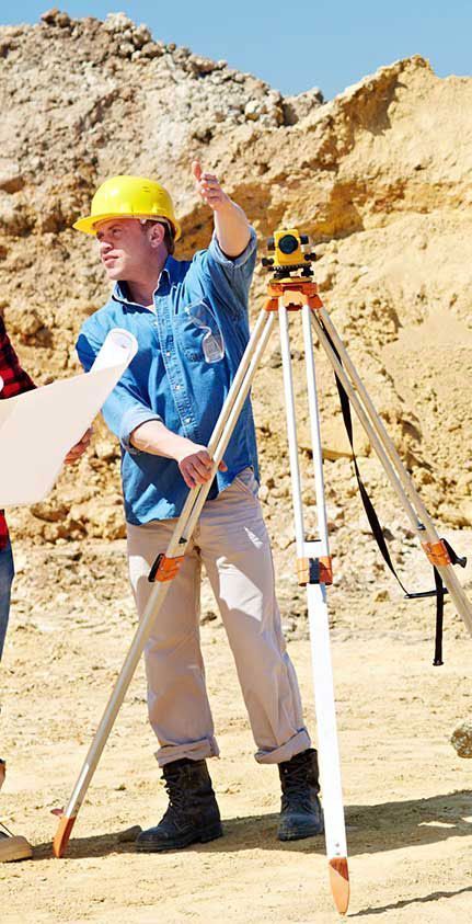 Un hombre con casco está de pie junto a un trípode.