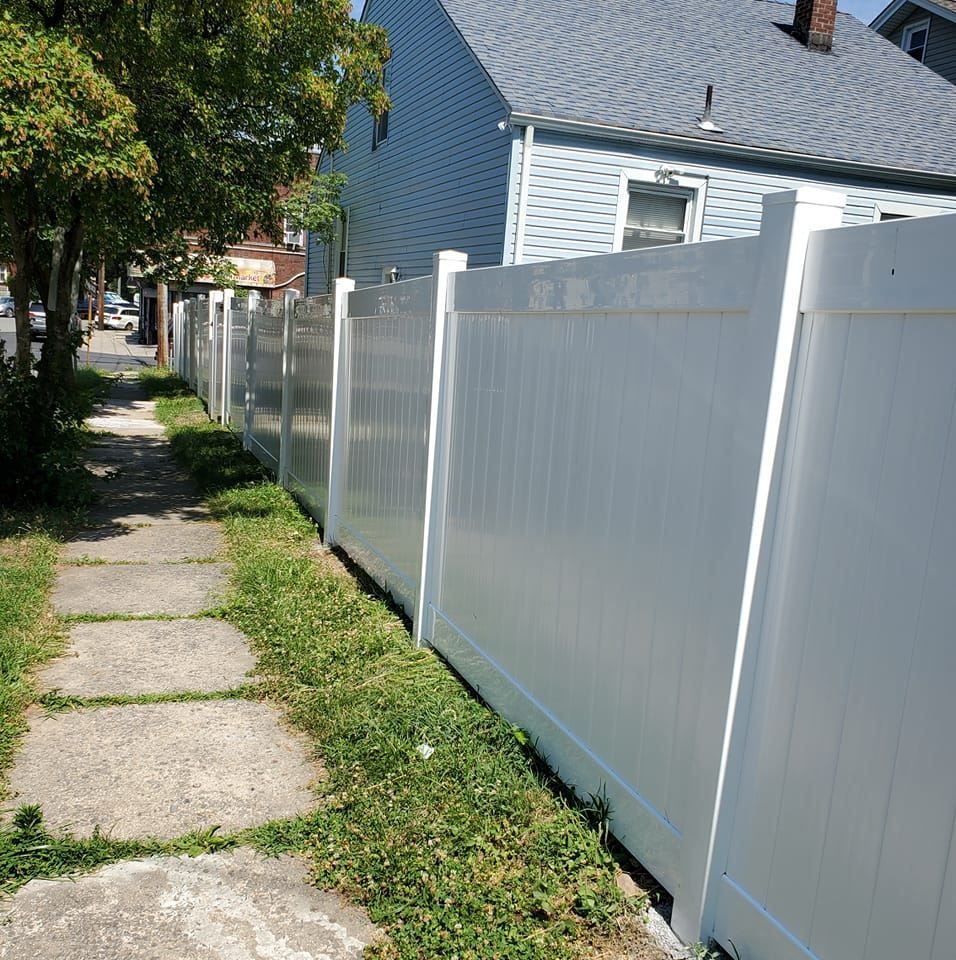 Woman in straw hat smiles, holding wine glass near a lake.