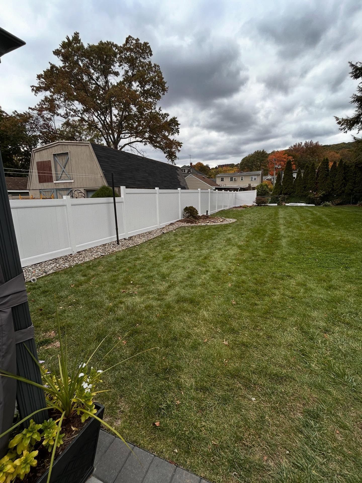 Woman in straw hat smiles, holding wine glass near a lake.