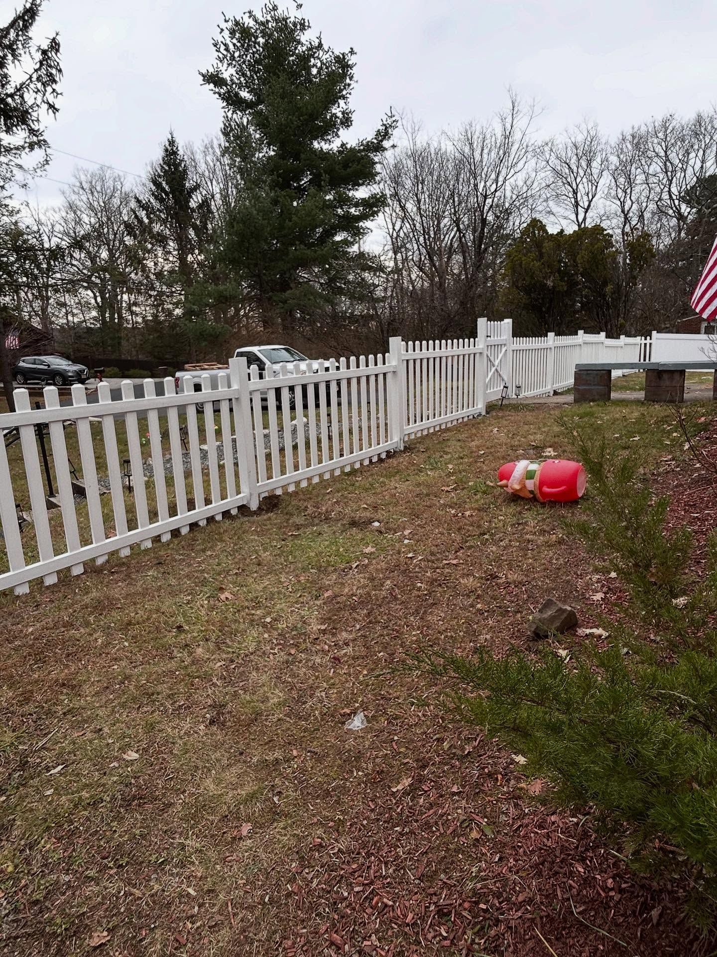Woman in straw hat smiles, holding wine glass near a lake.