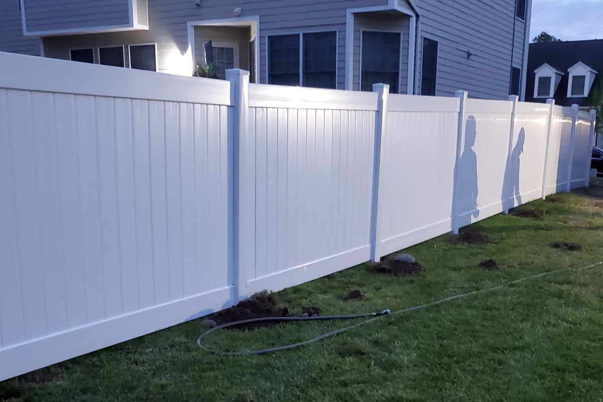Woman in straw hat smiles, holding wine glass near a lake.