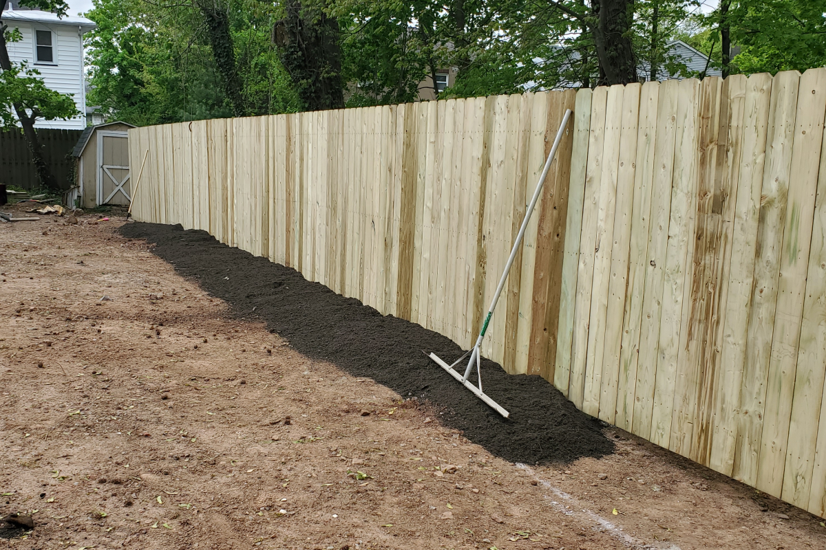 Woman in straw hat smiles, holding wine glass near a lake.