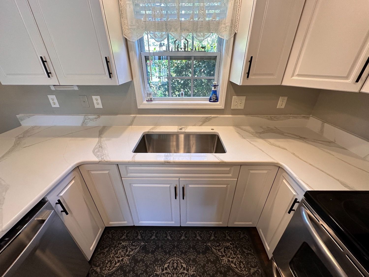 A kitchen with white cabinets and a stainless steel sink