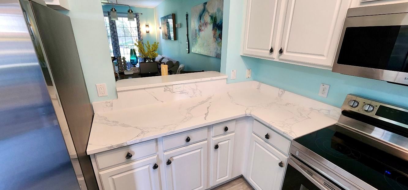 A kitchen with white cabinets , stainless steel appliances , a stove and a microwave.