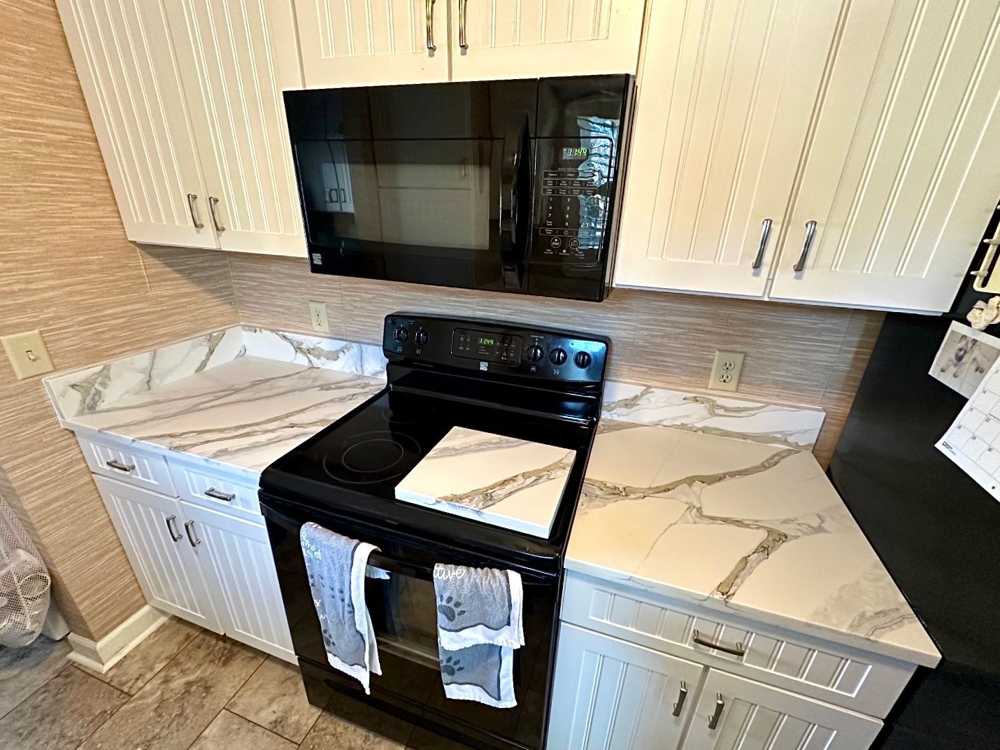 A kitchen with a black stove , microwave , and white cabinets.