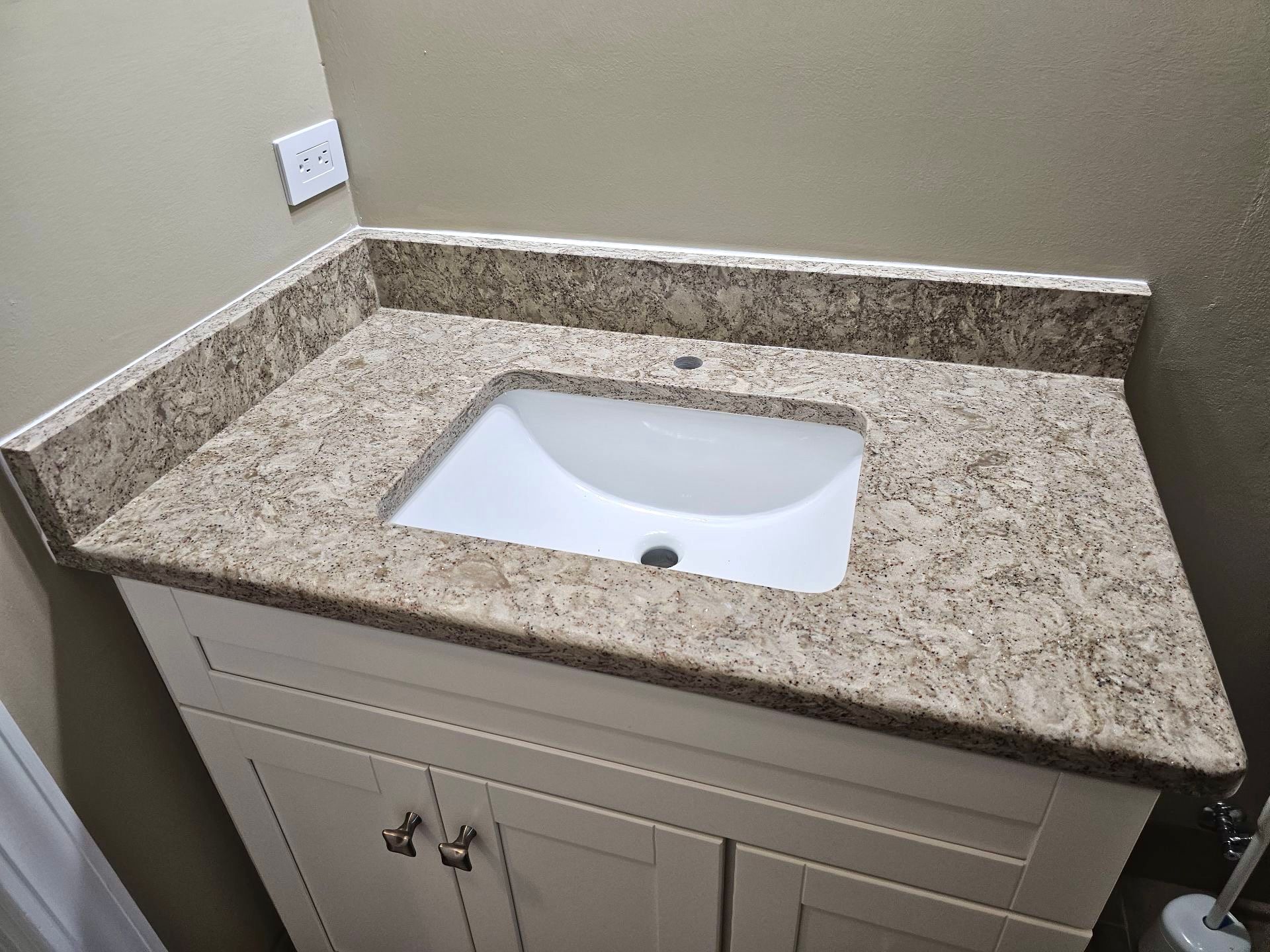 A bathroom vanity with a sink and granite counter top.
