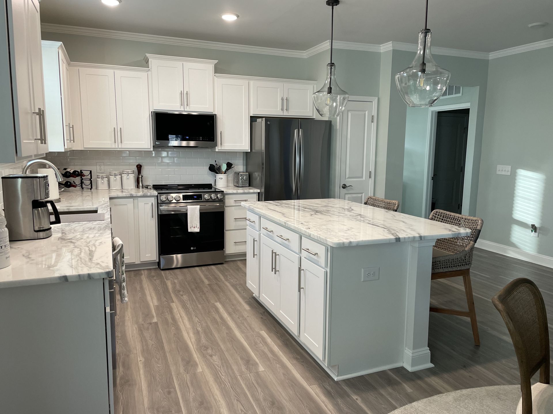 A kitchen with white cabinets , stainless steel appliances , and a large island.