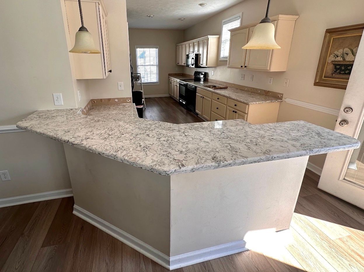 A kitchen with a granite counter top and white cabinets.