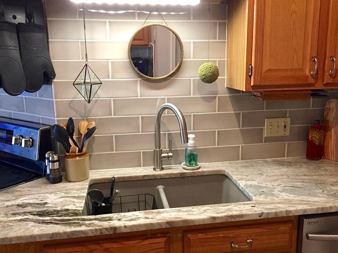 A kitchen with a sink , stove , and mirror.
