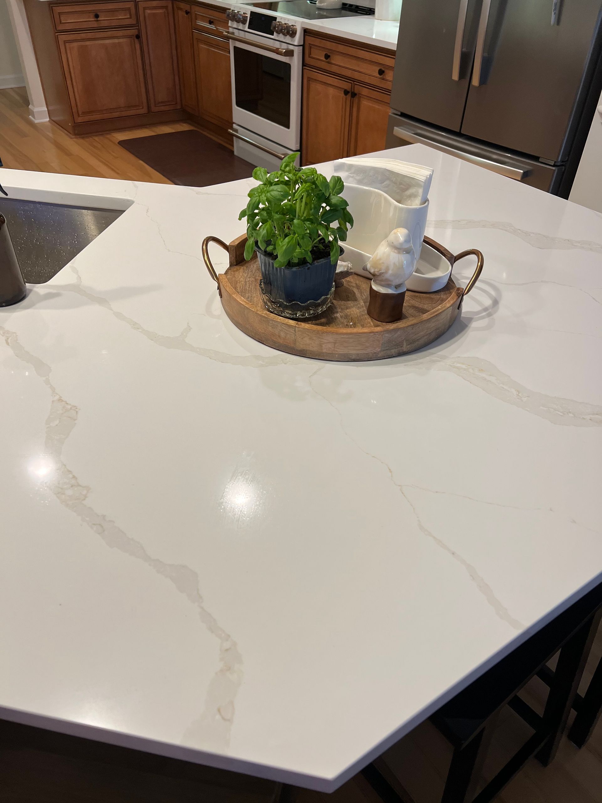 A white counter top with a wooden tray on it in a kitchen.