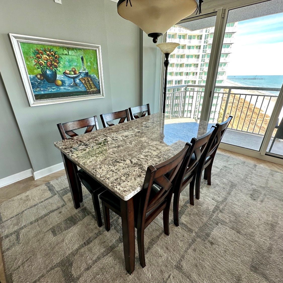 A dining room with a table and chairs and a painting on the wall