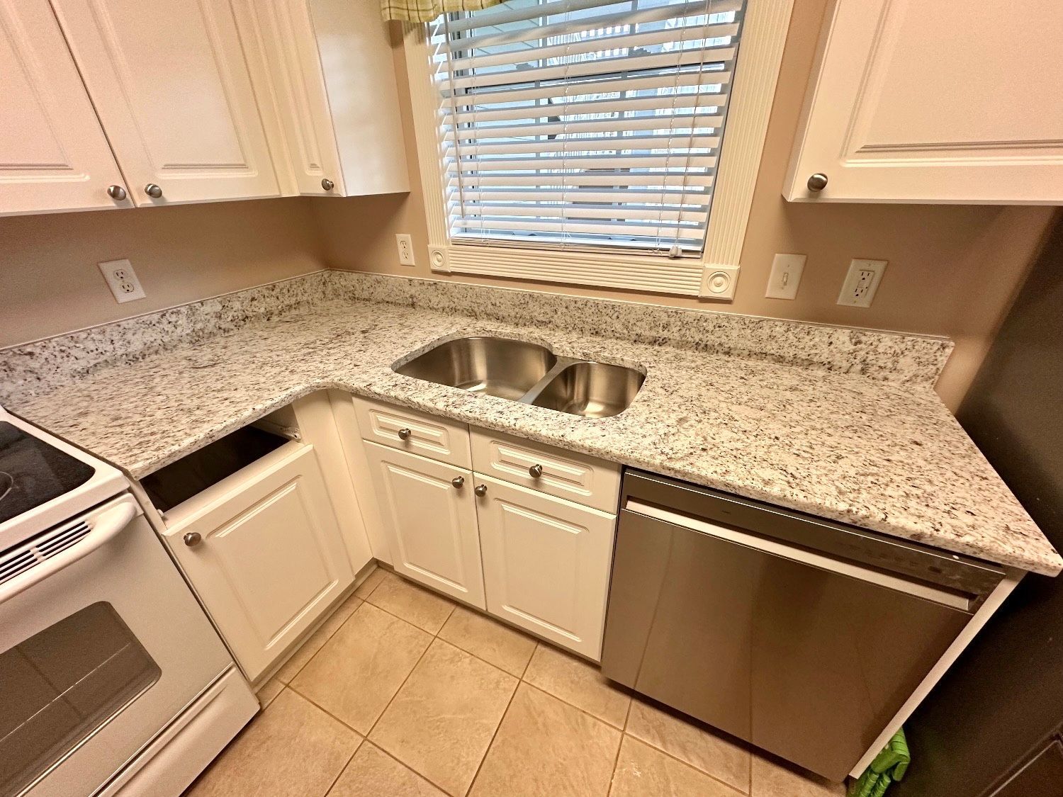 A kitchen with granite counter tops , stainless steel appliances , and white cabinets.