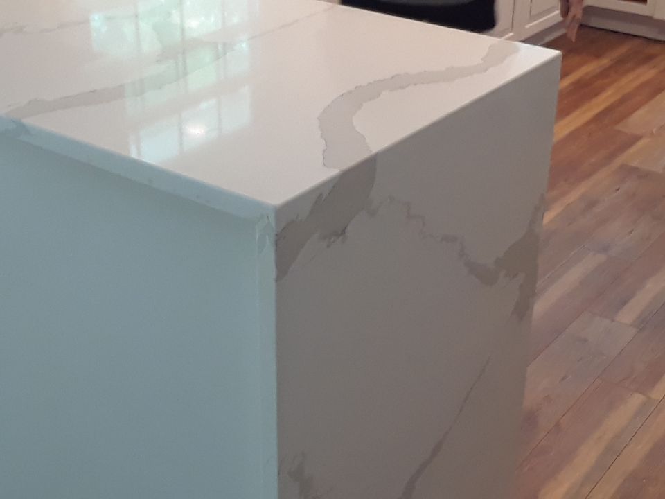 A white counter top with a wooden floor in a kitchen.