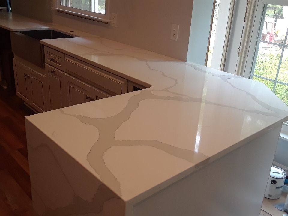 A kitchen with a large white counter top and a sink.