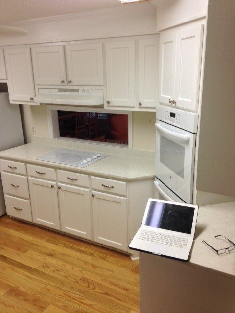 A kitchen with white cabinets and a laptop on the counter