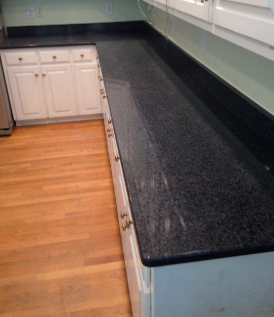 A kitchen with black granite counter tops and white cabinets