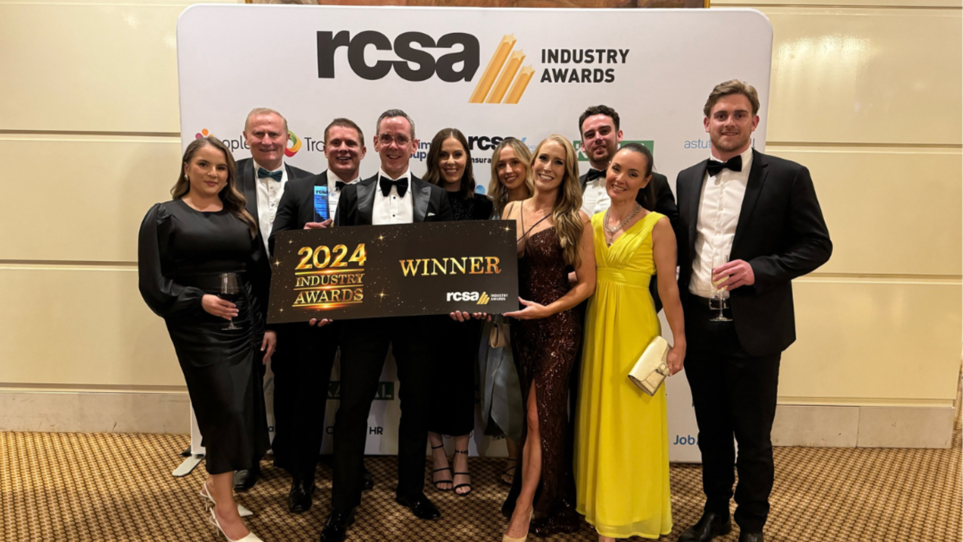 Group of people holding an award, celebratory setting. 