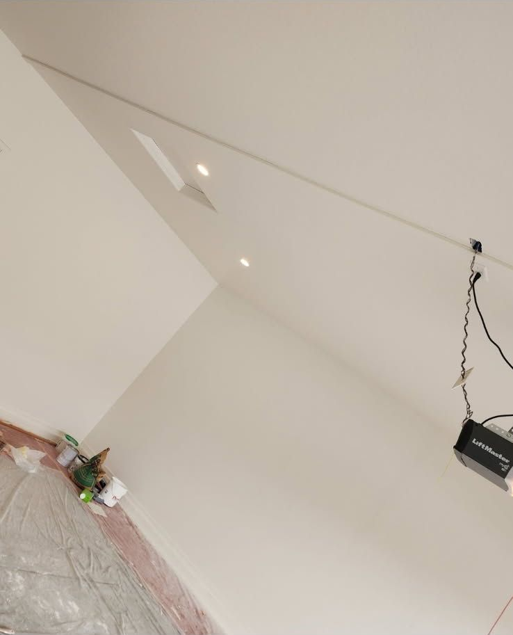 White walls and ceiling with recessed lights; unfinished construction setting.