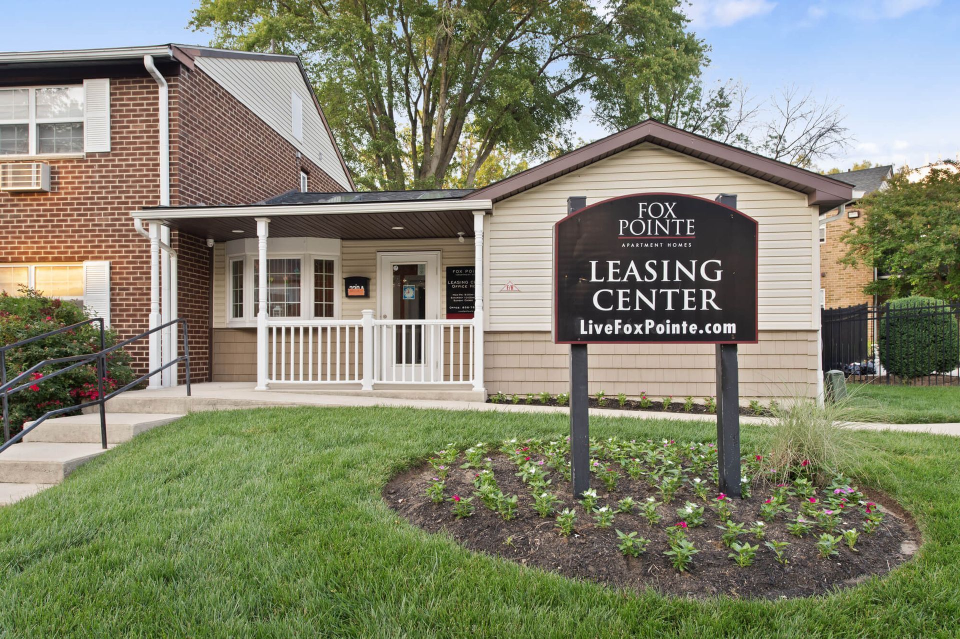 Exterior view of Fox Pointe Leasing Center with sign and landscaped garden.